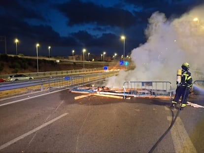 Un bombero sofoca una barricada en uno de los accesos a Cádiz por la huelga del metal.