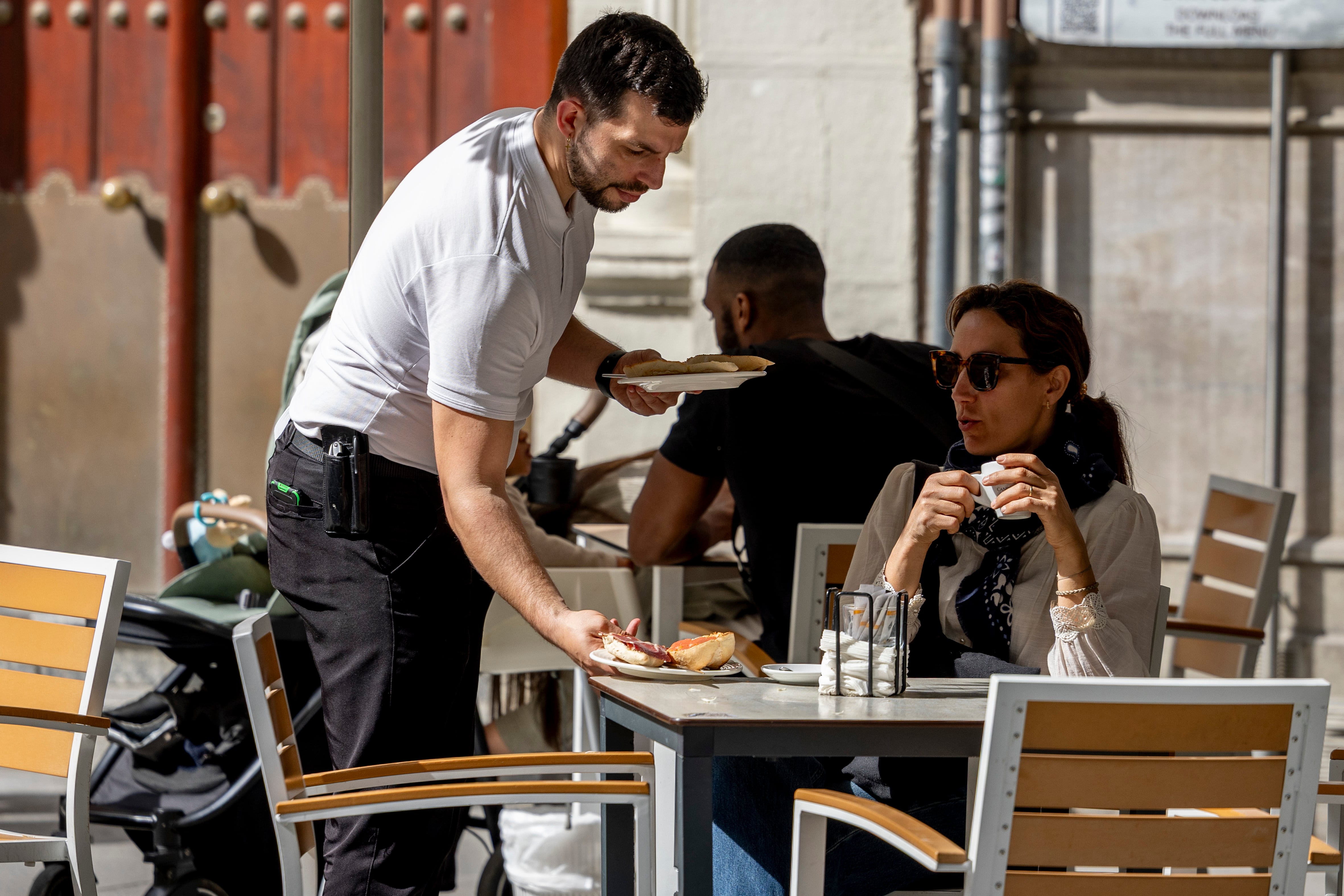Un camarero atiende a un cliente en una terraza de Sevilla