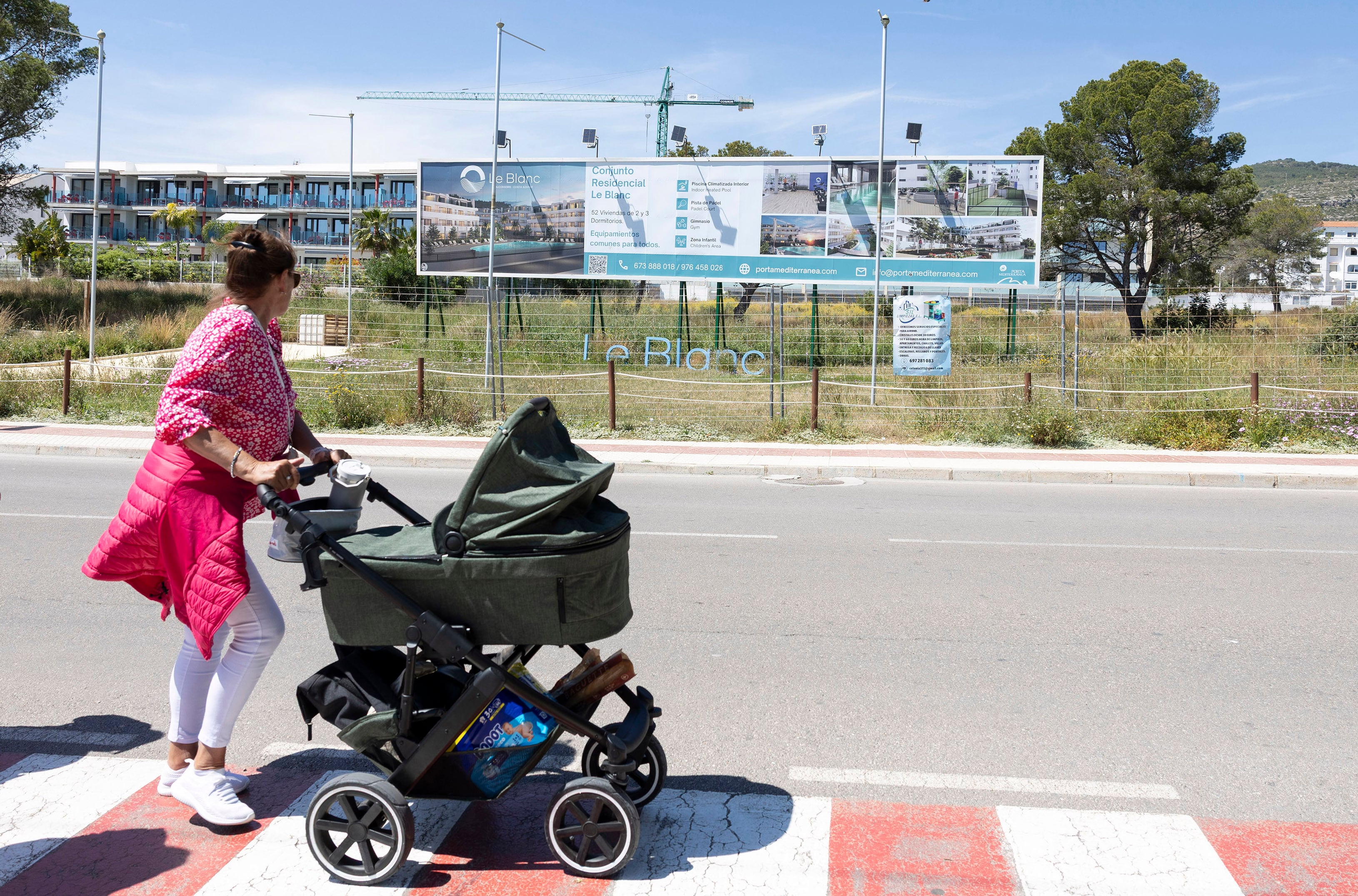 Una mujer pasa por delante de la zona en la que se construye una de las promociones de viviendas impulsadas por Porta Mediterrània en Alcocéber (Castellón).