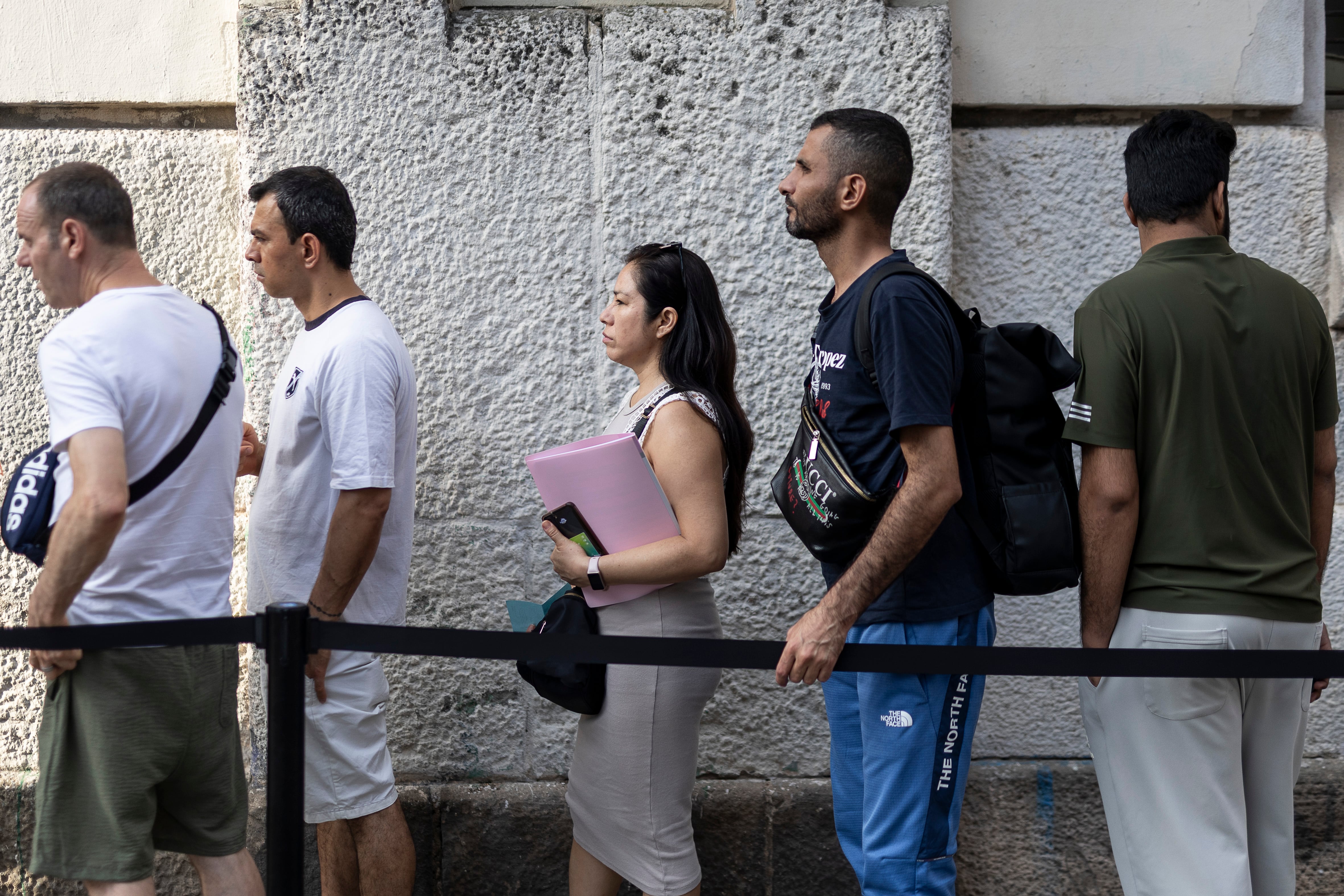 Varias personas que quieren acogerse al proceso extraordinario de regularización de migrantes hacen cola en las oficinas de Miquel Bleach del Ayuntamiento de Barcelona.